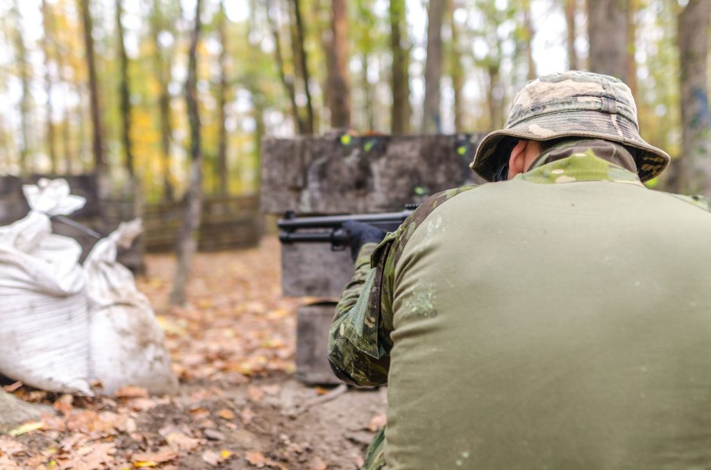 Joueur en tenue camouflage qui vise en forêt