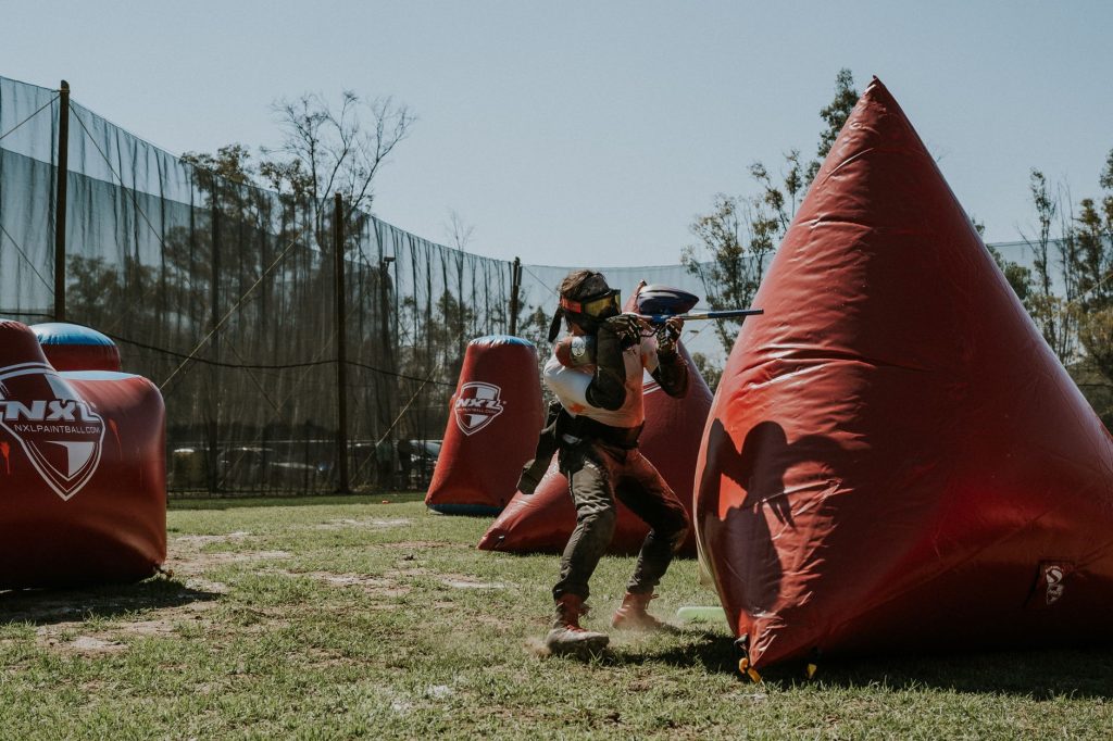 Joueur de paintball qui vise derrière un obstacle gonflable